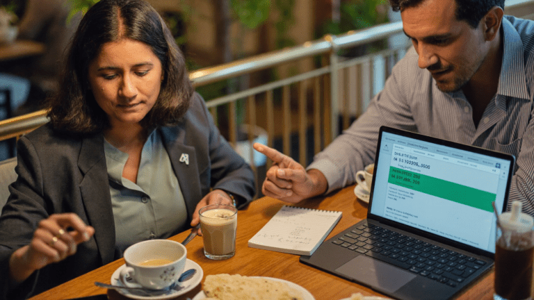 Pune cafe at 7:14 PM with CFO and CX head reviewing Freshworks HubSpot Zoho quotes on a Surface laptop with two chai cups and a printed pricing PDF