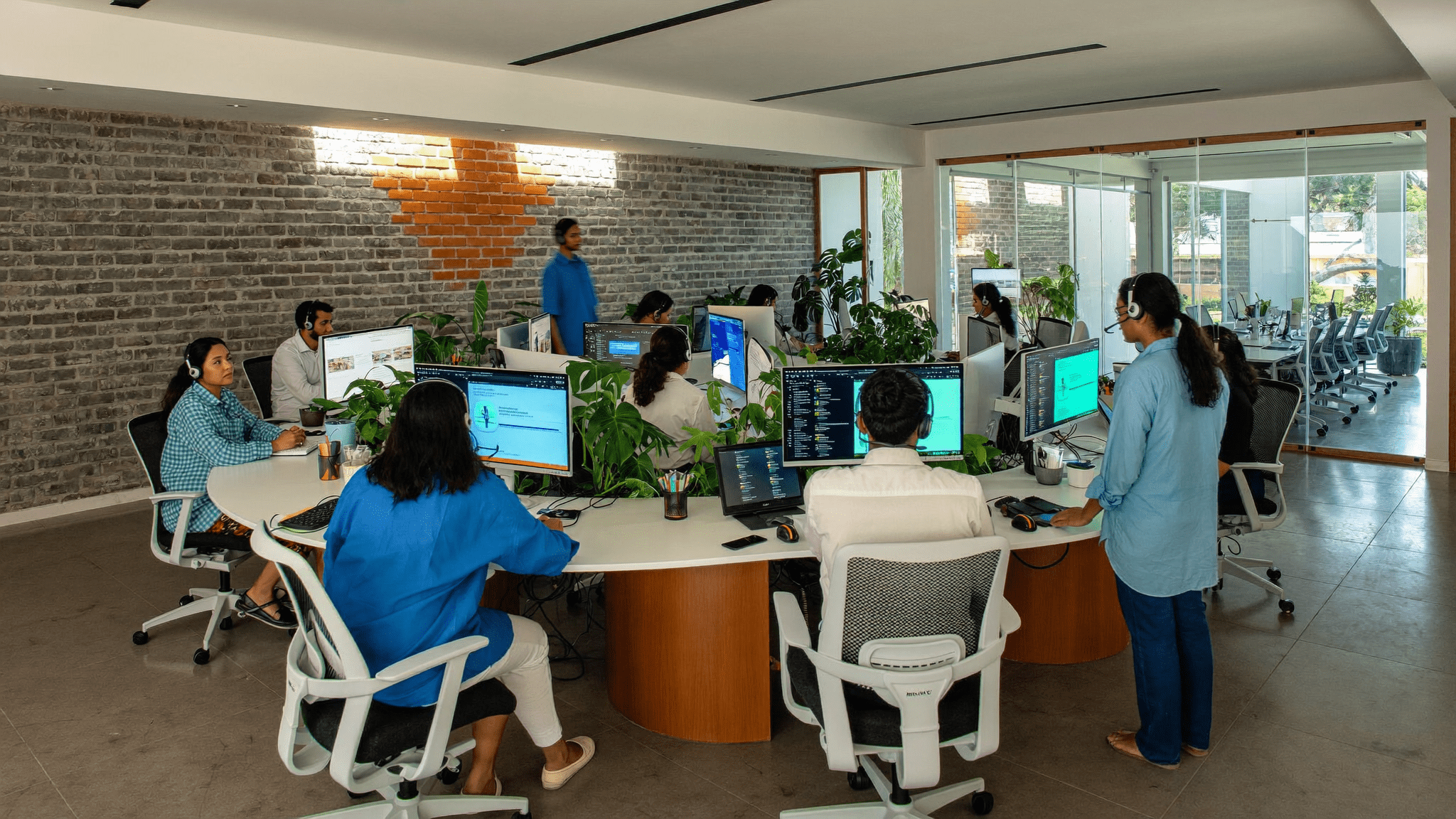 Pune SaaS customer support team at curved desks with dual monitors wearing headsets working calmly through Freshworks omnichannel queues at 11 AM