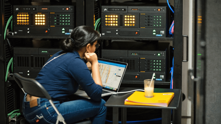 AMD EPYC server migration india: Pune fintech data hall, four HPE ProLiant DL325 Gen11 chassis racked with chassis intake temperature dashboard on a laptop in the foreground