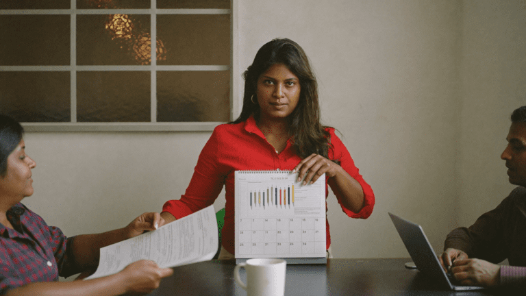 Indian HR head in Bengaluru fintech morning meeting with paper Diwali gifting calendar 12-week planning