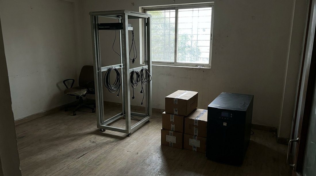 A nearly empty server room after a phased AWS migration, equipment boxed and one rack left with coiled cables