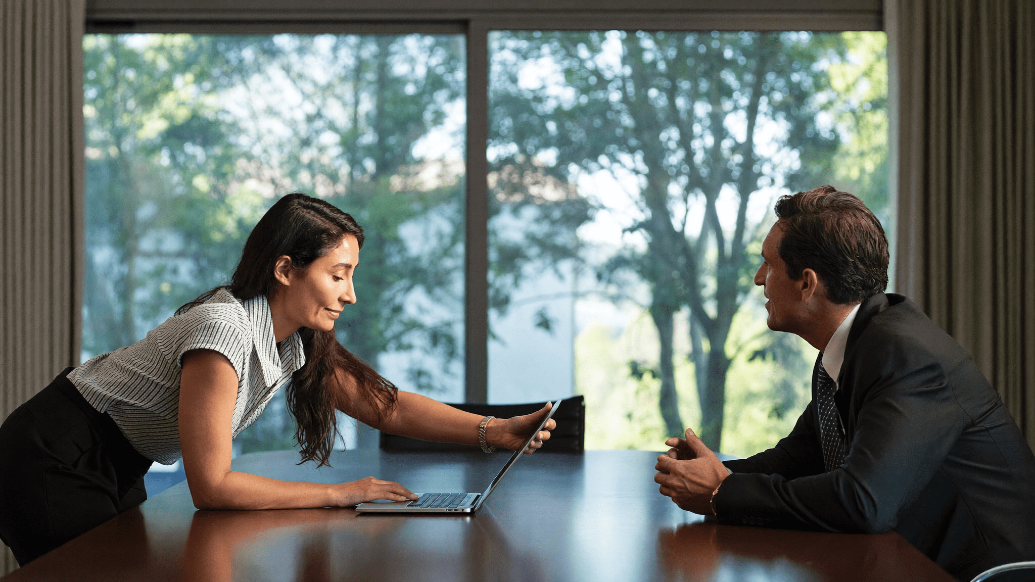 Indian IT manager leaning forward making her case to CFO across boardroom table