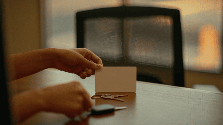 An employee's hands leaving a blank access card and office keys on a desk beside an empty chair in warm evening light